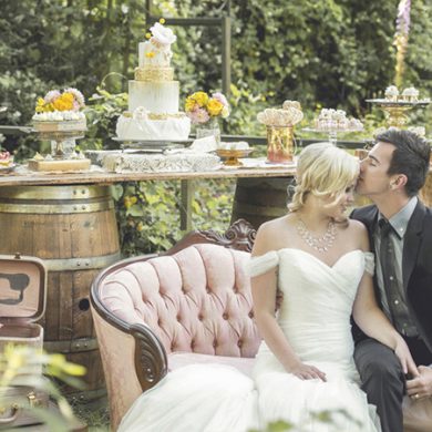 Couple lounging on vintage couch in front of a rustic dessert table.
