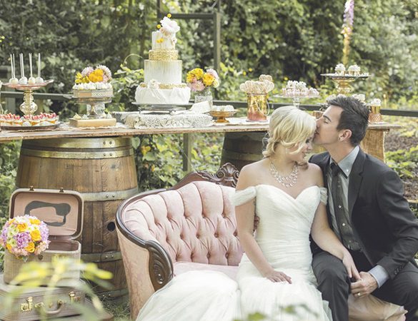 Couple lounging on vintage couch in front of a rustic dessert table.
