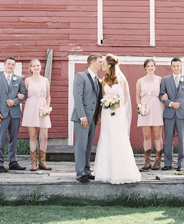 Wedding party posing in front of a red barn.